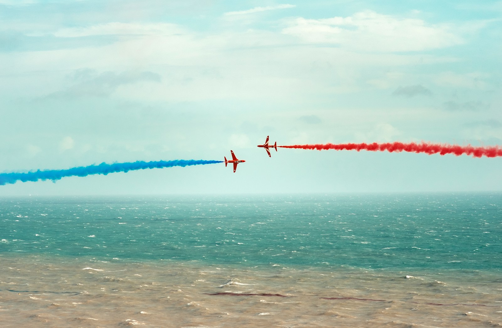 red and white plane flying over the sea during daytime